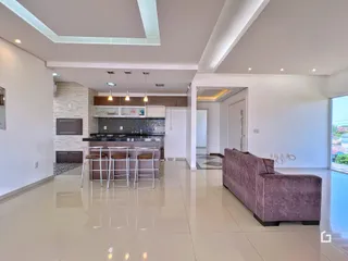 Sala de estar e cozinha de uma residência moderna com piso de cerâmica clara.