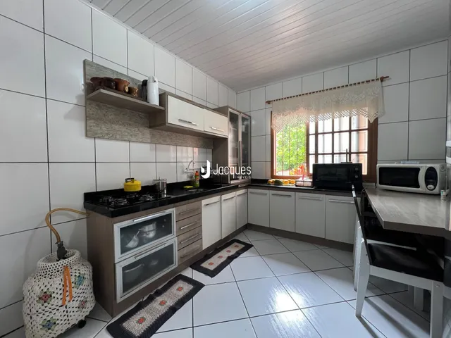 Vista da cozinha com armários e piso de cerâmica branca.
