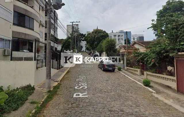 Vista externa de uma rua residencial em Lajeado, Brasil, mostrando edifícios e vegetação.