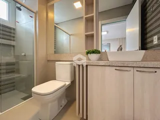 Foto de um banheiro com box de vidro e louças brancas.