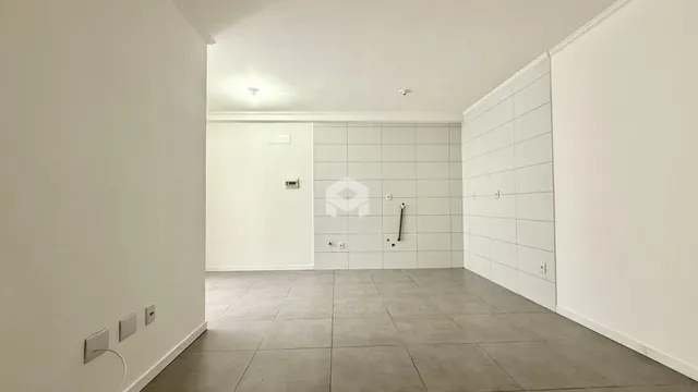 Vista interna de um corredor com paredes brancas e piso de cerâmica.