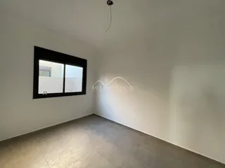 Ambiente interno com paredes brancas e piso claro, mostrando uma janela.