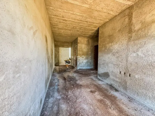 A foto mostra um corredor interno com paredes de concreto cru.