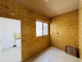 Corredor interno com paredes de azulejo amarelo e piso de cerâmica.