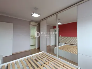 Quarto com cama de madeira e espelho refletindo o ambiente.