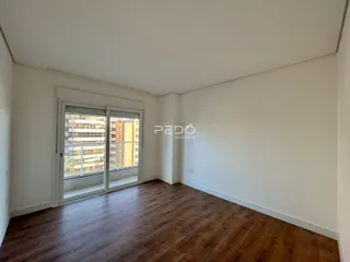 Ambiente interno com piso de madeira e porta de vidro de acesso à varanda.
