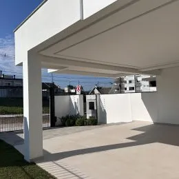 Área externa coberta com piso de concreto em uma residência.