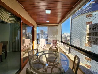 Vista de uma sala de jantar com mesa de vidro e vista para o exterior.