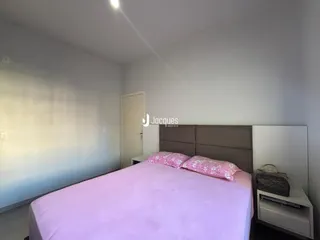 Quarto com cama rosa e paredes brancas.