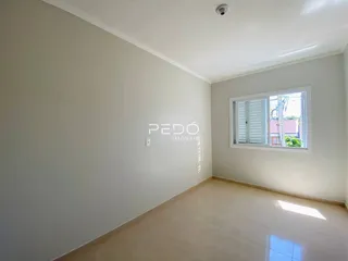 Interior de uma sala com paredes brancas e piso claro.