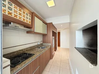 Vista da cozinha de uma residência em Lajeado, Brasil com armários de madeira e bancadas de granito.