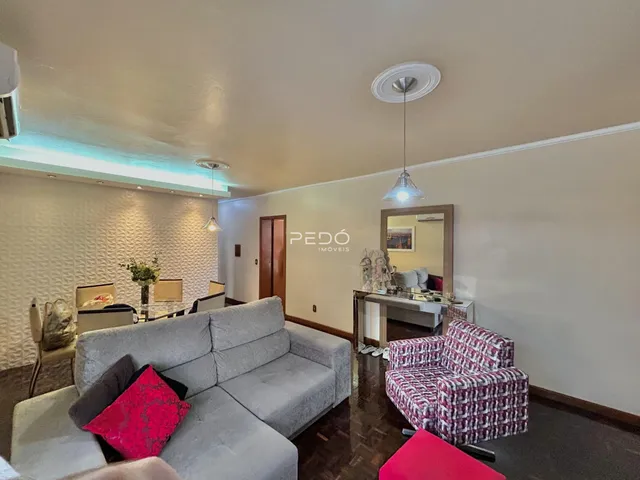 Sala de estar com sofá cinza e piso de madeira no imóvel.