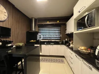 Cozinha moderna com armários brancos e detalhes em madeira.