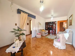Sala de estar com piso de madeira e cortinas claras.