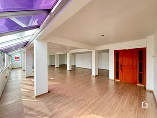 Corredor interno com piso de madeira e porta vermelha em um imóvel.