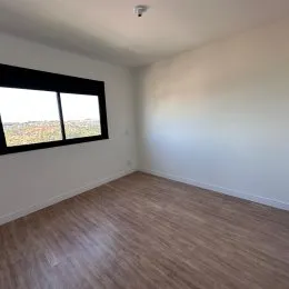 Foto de um ambiente interno com piso de madeira e uma grande janela.