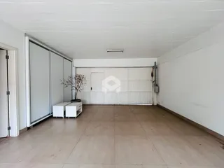 Interior de uma área ampla com porta de garagem branca e paredes brancas.