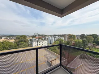 Vista panorâmica de uma área residencial com edifícios e vegetação ao fundo.