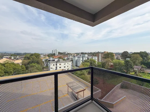 Vista panorâmica de uma área residencial com edifícios e vegetação ao fundo.