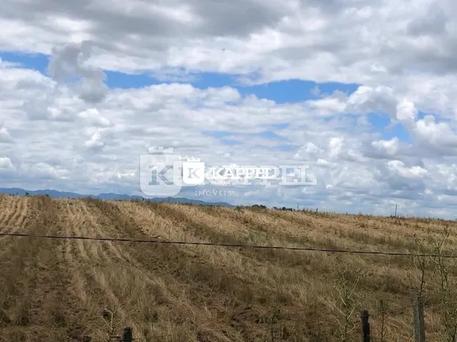 Paisagem de campo seco e colinas sob um céu nublado.