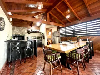 Ambiente de jantar com teto de madeira e piso de tijolos na residência.