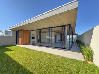 Fachada moderna de uma residência com grandes portas de vidro e jardim em Lajeado, Brasil.
