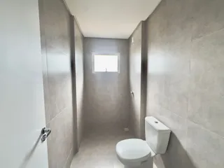 Foto de um corredor estreito com um vaso sanitário branco e uma janela no final.