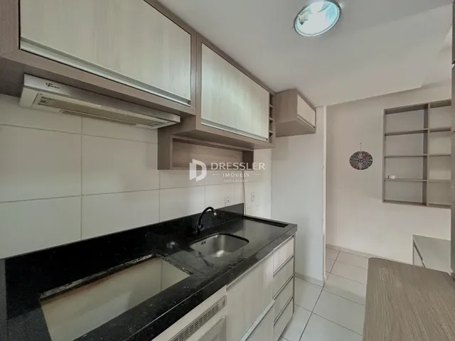 Cozinha moderna com armários brancos e bancada escura.
