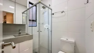 Banheiro moderno com box de vidro e revestimento branco.