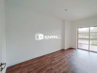 Uma sala ampla com piso de madeira e grande janela.
