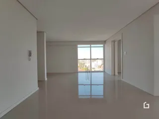 Interior de uma sala ampla com paredes brancas e piso claro.