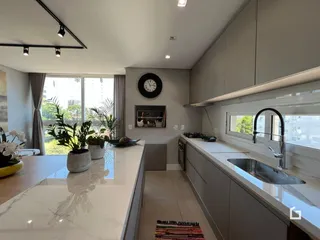 Vista da cozinha moderna com bancada clara e janela.