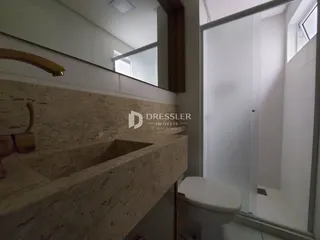 Foto de um banheiro com bancada de mármore e vaso sanitário branco.
