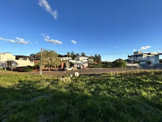 Vista externa de uma propriedade com gramado e casas ao fundo.
