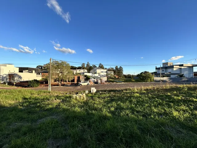 Vista externa de uma propriedade com gramado e casas ao fundo.