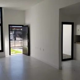 Hall de entrada com paredes brancas e porta de vidro.