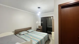 Quarto com cama de casal e paredes brancas.