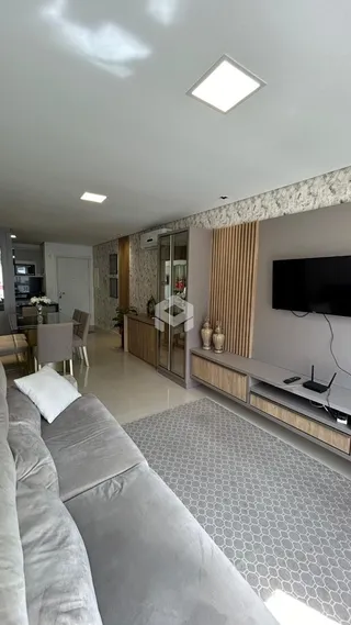 Sala de estar com sofá cinza e televisão na parede.