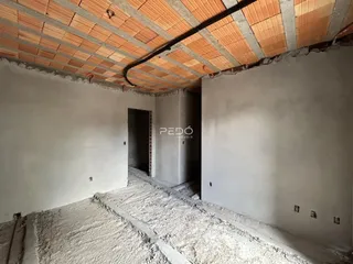 Foto de uma área interna em construção com paredes e teto expostos.