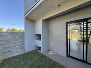 Vista externa de uma parede de concreto e área gramada de uma residência.