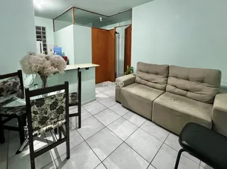 Foto de uma sala de estar com sofá e mesa de jantar em um apartamento.