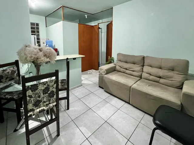 Foto de uma sala de estar com sofá e mesa de jantar em um apartamento.
