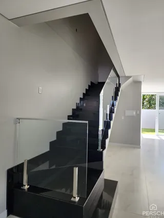 Foto de uma escadaria escura com guarda-corpo de vidro em um interior.