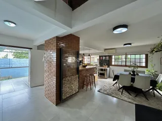 Ambiente de sala de estar e jantar com parede de tijolos aparentes em Lajeado.