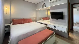 Quarto com cama e televisão montada na parede em um apartamento.