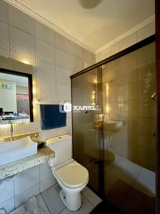 Foto de um banheiro com revestimento de azulejos brancos e um vaso sanitário.