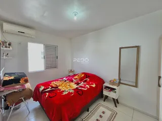 Quarto com cama vermelha e janela em ambiente claro.