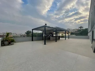 Área externa pavimentada com estrutura de pergolado.
