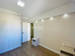 Ambiente interno de uma sala com piso de madeira clara e parede decorada.