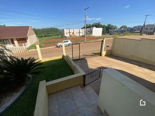 Vista externa de um pátio com cerca e gramado em uma residência.